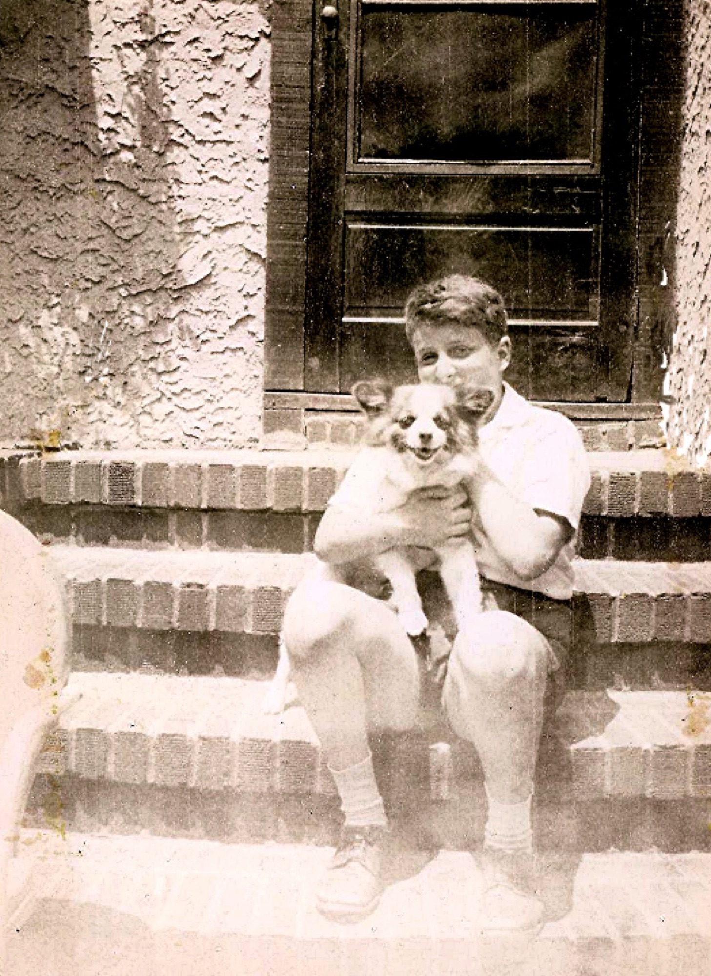 A young Marshall holding Bunny on the steps in Laurelton in 1950
